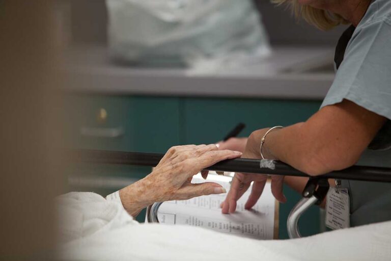 Older adults walking with canes along a well-lit hallway with handrails and uncluttered floors.